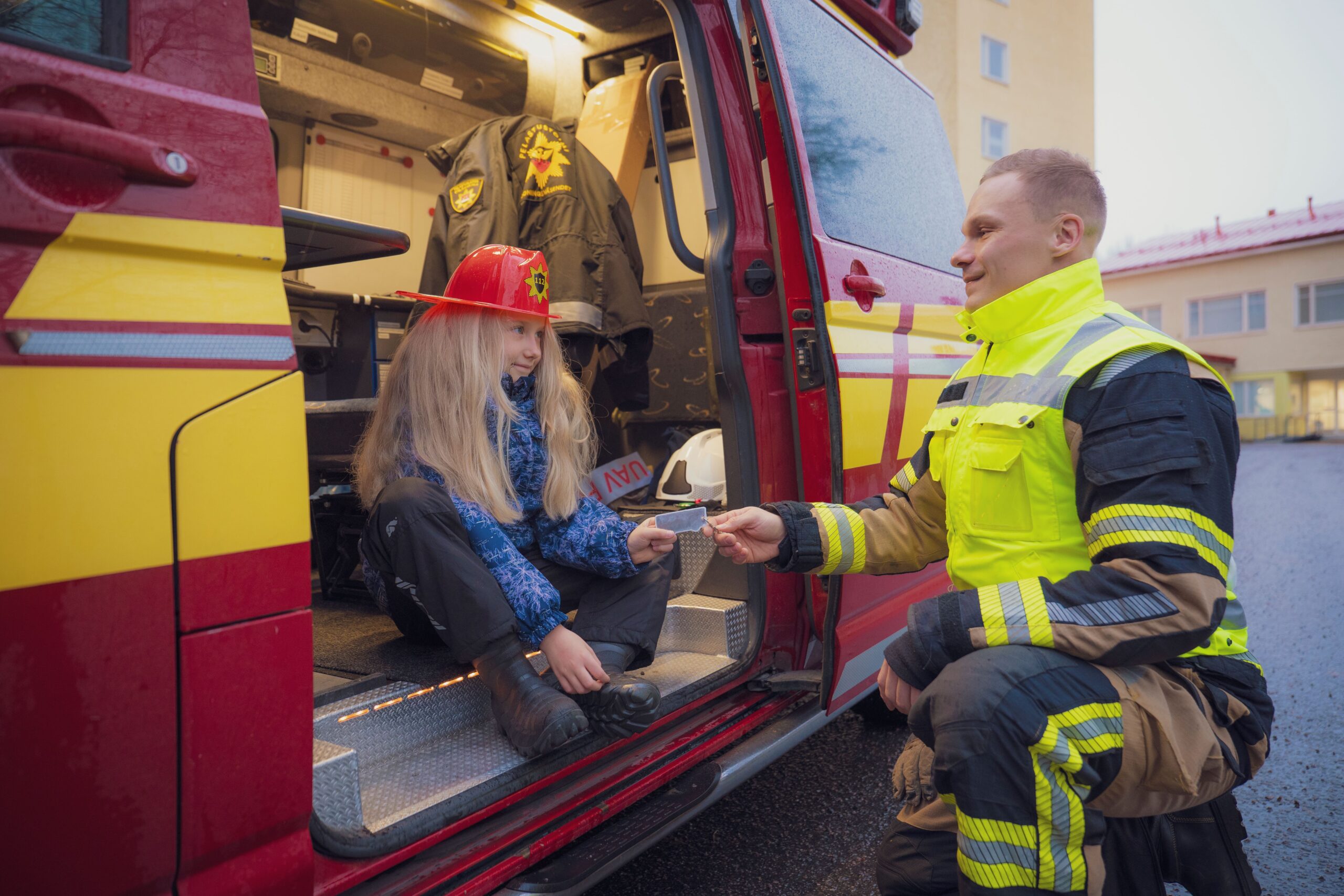 Palomies ojentaa pitkähiuksiselle pienelle tytölle heijastinta